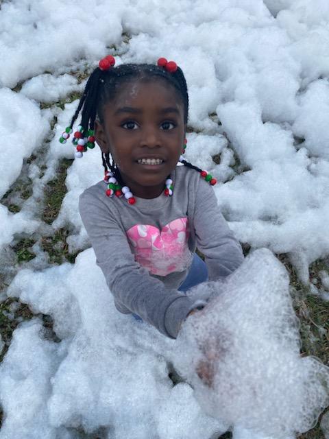 girl playing at park in snow foam 