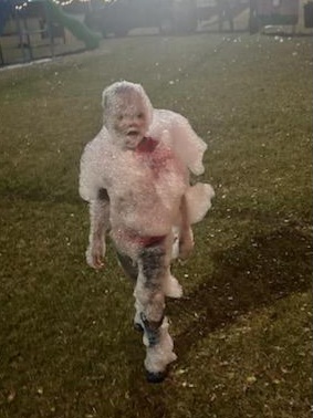 kid covered in snow foam at park